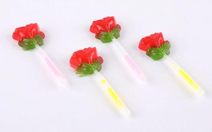La fluorescenza accende la lecca-lecca di forma del fiore di Candy Rosa con il bastone di illuminazione